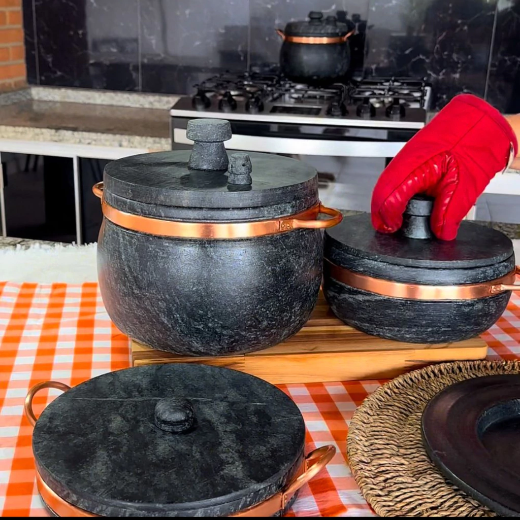Jogo de panelas de pedra-sabão com alças de cobre sobre a mesa